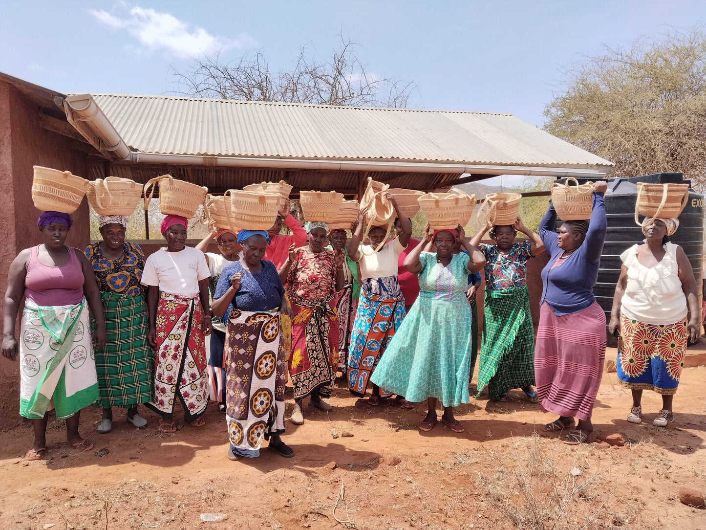 A group of female Kenyan artisans holding hand-woven baskets on their heads