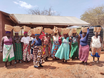 A group of female Kenyan artisans holding hand-woven baskets on their heads